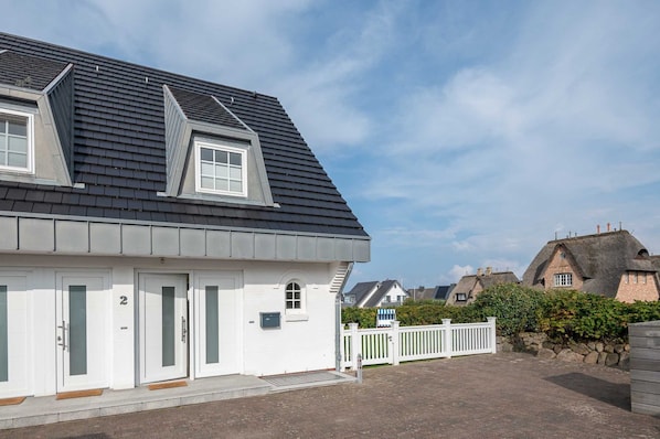 A modern house with a grey roof, white exterior walls, and a small porch.