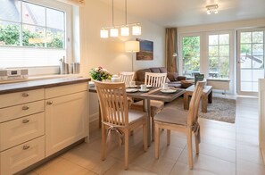 Una cocina moderna con armarios de madera, una mesa de comedor preparada para cuatro personas y una sala de estar acogedora con un sofá y una mesita de centro.
