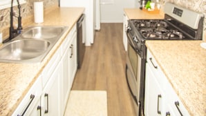 A kitchen with white cabinets, stainless steel appliances, and a wooden floor.