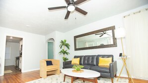 A living room with a ceiling fan, a sofa, a coffee table, a lamp, and a mirror.