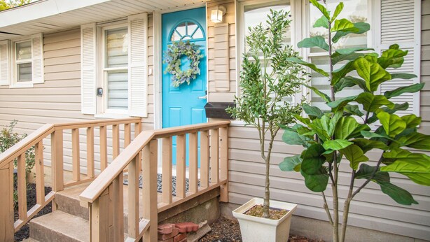 A house with a blue door, a wooden staircase, and a potted plant.