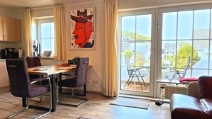 Ein modernes Wohnzimmer mit Essbereich, großen Fenstern und Blick auf die Stadt.