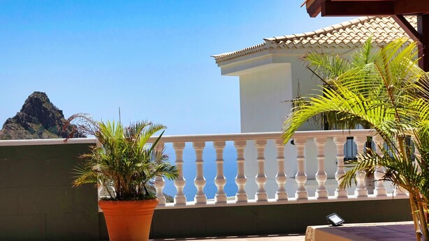 En balkon med udsigt til et bjerg, et hvidt gelænder og plantekasser.