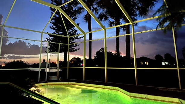 Une piscine couverte offrant une vue sur les palmiers et un coucher de soleil.