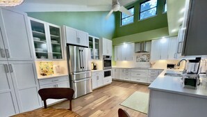 Una cocina moderna con armarios blancos, electrodomésticos de acero inoxidable y una mesa de comedor de madera.