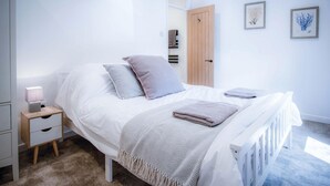 A bedroom with a bed, bedside table, and a nightstand. - The Cottage - 2 Bedroom Cottage - Tenby (Tenby)