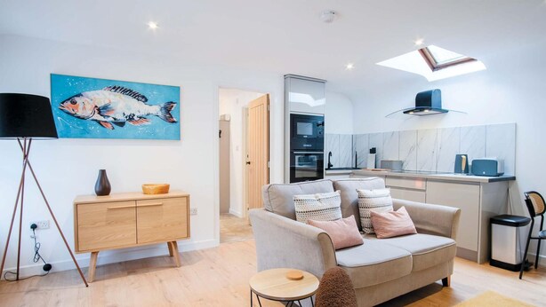 A modern living room with a sofa, a coffee table, and a painting of a fish.