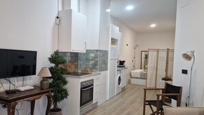 Una cocina moderna con horno empotrado, lavadora y comedor con mesa y sillas.