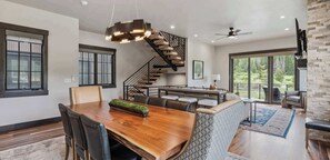 A modern dining area with a wooden table, chairs, and a unique hanging light fixture.