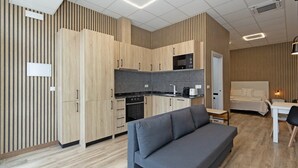 Een moderne, compacte leefruimte met een kitchenette, een bank, een bed en een eethoek.