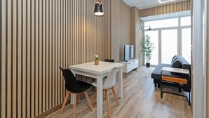 Een moderne eethoek met een witte tafel, zwarte stoelen en een hanglamp.