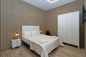Ein Schlafzimmer mit Bett, Nachttischen, einem Kleiderschrank und einem Sessel.