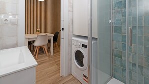 Un bagno compatto con lavandino, lavatrice e box doccia.