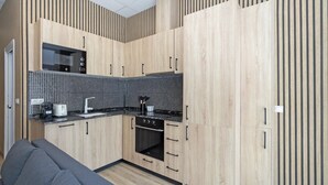 Una cucina compatta con mobili in legno, zoccolo a scacchi in bianco e nero e un piano cottura moderno.