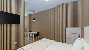 Una camera d'albergo moderna con un letto, un comodino e una scrivania con sedie.