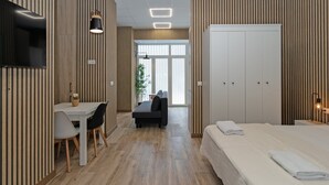 A modern hotel room with a wooden floor, a bed, a desk with a chair, a sofa, and a wardrobe. - GuestReady Essential- Blissful stay near the beach (Valencia)