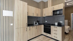 A modern kitchen with wooden cabinets, a black countertop, and a tiled backsplash. - GuestReady Essential- Blissful stay near the beach (Valencia)