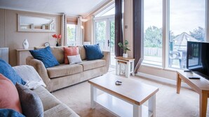 A living room with a beige sofa, a wooden coffee table, and a TV on a wooden stand.