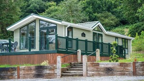 A two-story lodge with a green exterior, large windows, and a wooden deck.