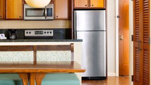 A kitchen with wooden cabinets, a stainless steel refrigerator, a microwave, and a coffee maker. - Disney Aulani Two Bedroom Poolside Villa! (Kapolei)