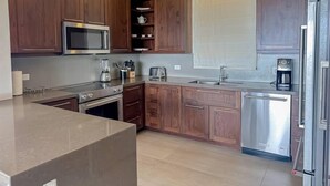 Een moderne keuken met houten kastjes, roestvrijstalen apparatuur en een groot eiland.