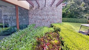 Ingang van een fitnesscentrum, met een stenen muur en een bord waarop staat: VISTA LOS SUENOS FITNESS CENTER.