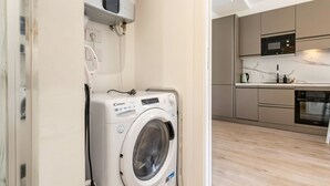 Una cucina funzionale con elettrodomestici moderni, una lavatrice e una presa elettrica a vista.