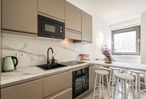 Een moderne keuken met een inbouwoven, een magnetron, een spoelbak en een raam voor natuurlijk licht.