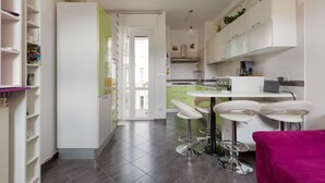 A modern kitchen with a dining area, including a bar stool setup and a kitchen island. - GuestHost - APT in the NOLO neighborhood! 500m from the M1 subway! (Milano)