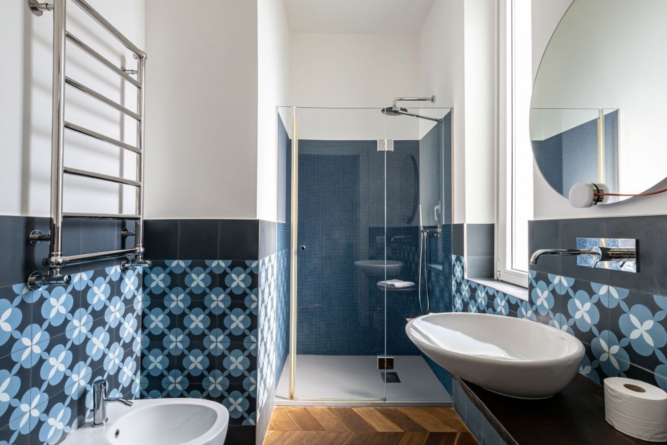 A modern bathroom with a glass shower enclosure, a white sink, and a toilet.