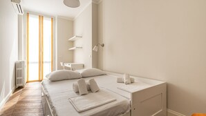 A bedroom with a bed, bedside tables, a radiator, and a window with curtains.