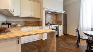 A modern kitchen with white cabinets, a wooden island, a built-in oven, and a dining area with a table and chairs.