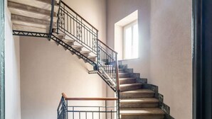 A spiral staircase with a metal railing and wooden handrails, leading to a landing.