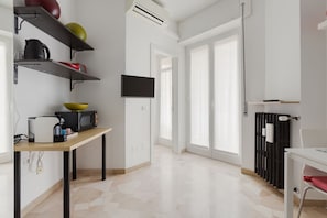 A modern kitchen with a flat-screen TV, a dining table, and a radiator.