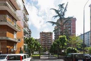 A multi-story residential building with balconies, a gated entrance, and a clear sky.