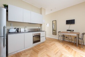Une cuisine moderne avec des meubles blancs, un four encastré et un coin repas comprenant une table et des chaises.