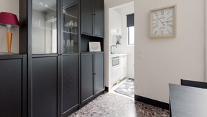 Una cocina con armarios oscuros, una vitrina de cristal, un reloj y suelo a cuadros.