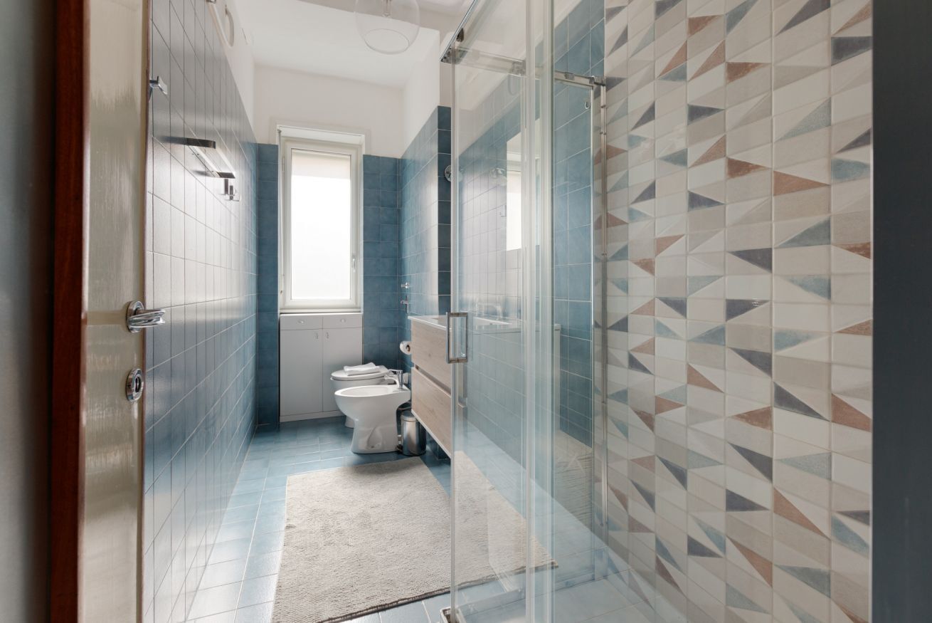 A bathroom with a glass shower enclosure, a toilet, and a sink.