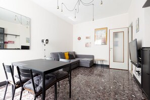 A modern living room with a dining table, sofa, and television.