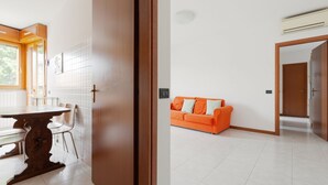 Eine moderne Küche mit Esstisch und Stühlen, einem hellen Fenster und einem Fliesenboden.