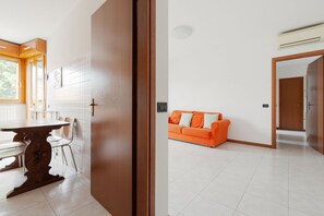 A modern kitchen with a dining table and chairs, a bright window, and a tiled floor.
