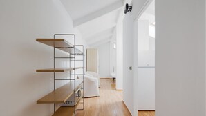 Ein modernes, minimalistisches Zimmer mit Holzboden, weißen Wänden und einer eingebauten Regaleinrichtung.