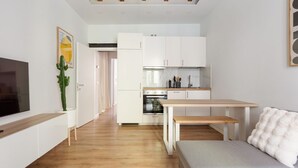 Una cocina moderna con armarios blancos, horno empotrado y mesa de comedor de madera.