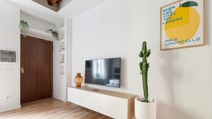 Una sala de estar moderna con un televisor de pantalla plana, un mueble de madera, una planta de cactus y un cartel motivacional en la pared.