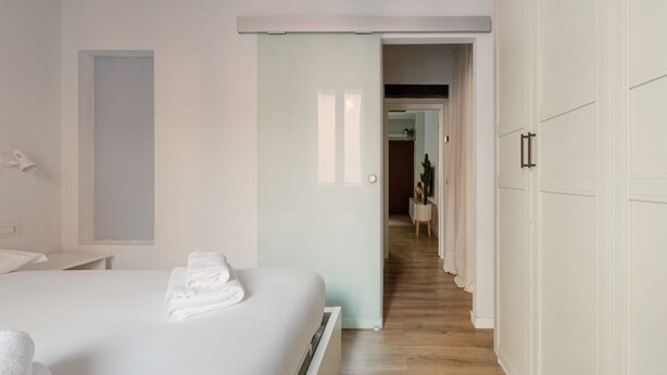 Una habitación de hotel con una cama, una puerta que da a un pasillo y un armario.