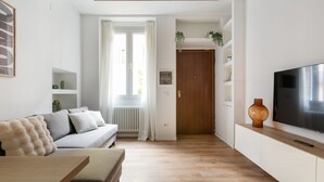 Una sala de estar moderna con un sofá, una mesa de centro, un televisor y piso de madera.