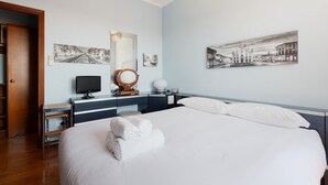 Habitación de hotel con una cama grande, una mesita de noche con lámpara, un espejo y obras de arte en las paredes.