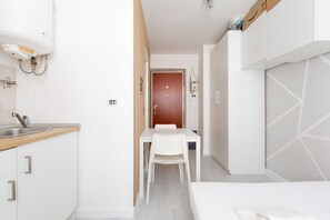 A compact hotel room with a kitchenette, a dining area, and a bed.