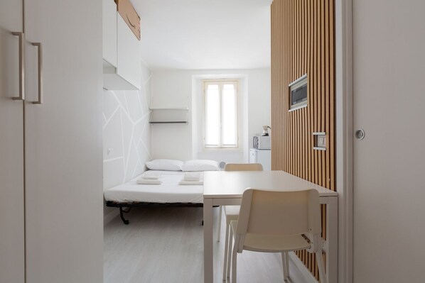A compact room with a bed, a table, and a chair.