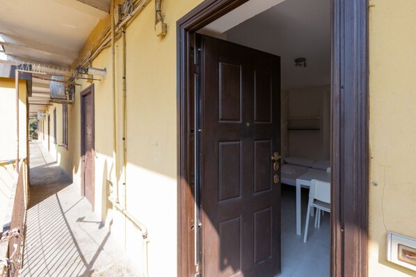 A narrow hallway with a door leading to a room with a bed and a small table.